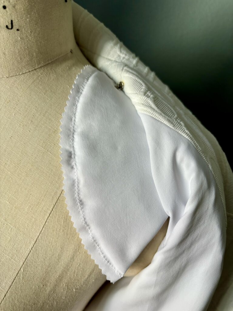 White peplum moto jacket handmade in textured fabric; shoulder pad close up